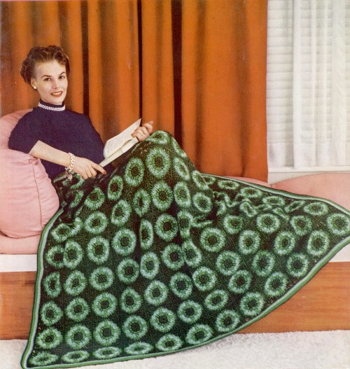 1952 tarihli kitapçıktan: kanepede kitap okuyan kadının dizine serilmiş yeşil tonlarında motifli battaniye
