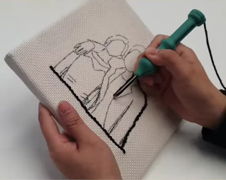 Çerçeveye gerilmiş kumaşa çizilen desenin çizgisini punch iğnesiyle işleyen eller (örnek görsel)